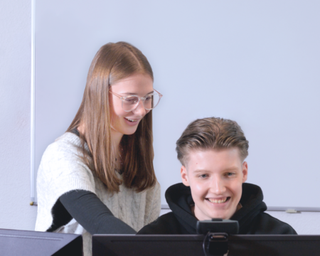 eine junge Frau zeigt einem jungen Mann etwas auf einem Bildschirm