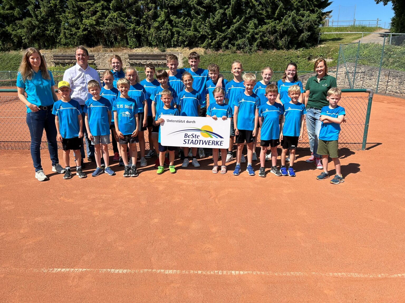 Eine Gruppe Kinder steht auf einem Tennisplatz