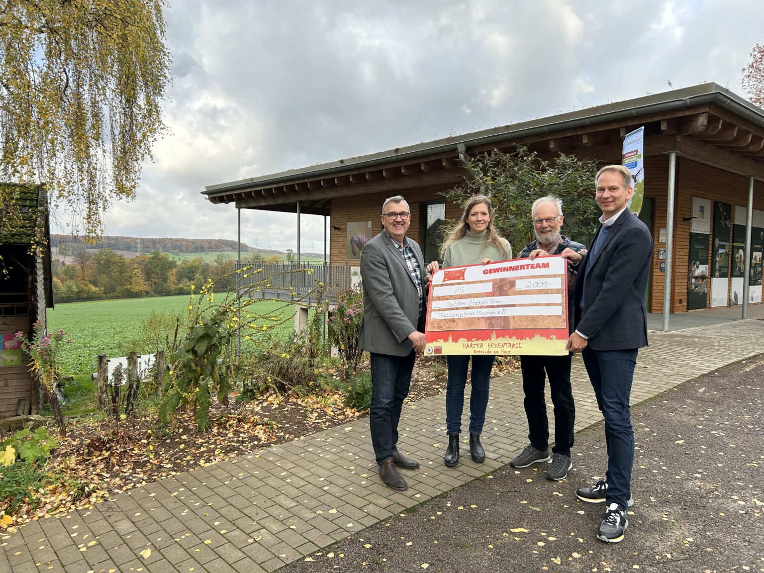 Vier Personen stehen vor einem Haus und halten einen Spendencheck in den Händen