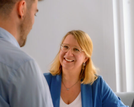 Es ist ein Gespräch zwischen einer Frau und einem Mann im Arbeitskontext zu sehen.