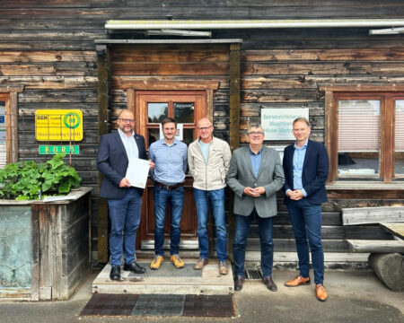 Fünf Männer stehen vor der Tür eines Holzhauses