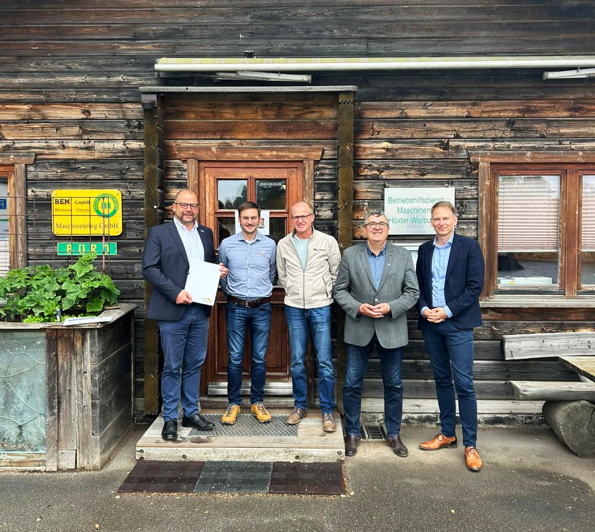Fünf Männer stehen vor der Tür eines Holzhauses