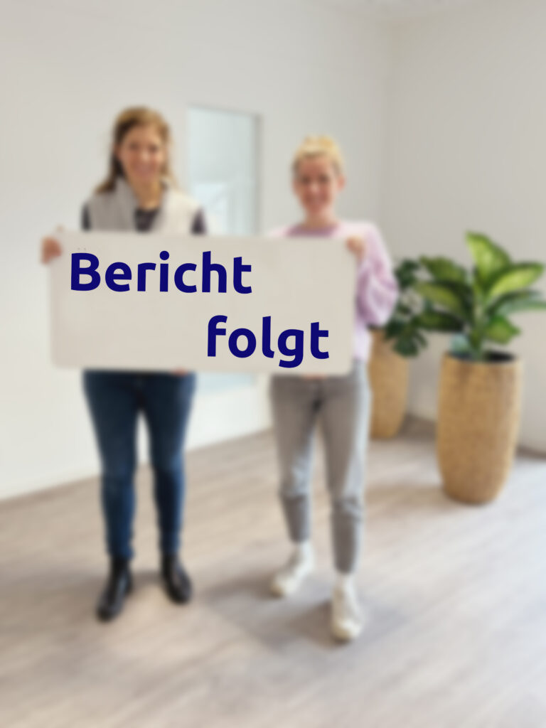 Zwei Frauen (unscharf) halten ein Schild in der Hand auf dem steht Bericht folgt