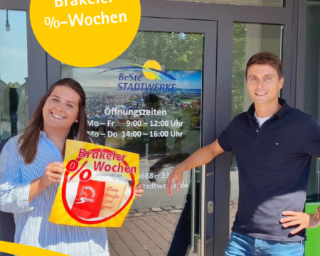 Eine Frau und ein Mann stehen vor der Eingangstür unseres Kundenbüros. Die Frau halt ein Plakat in der Hand